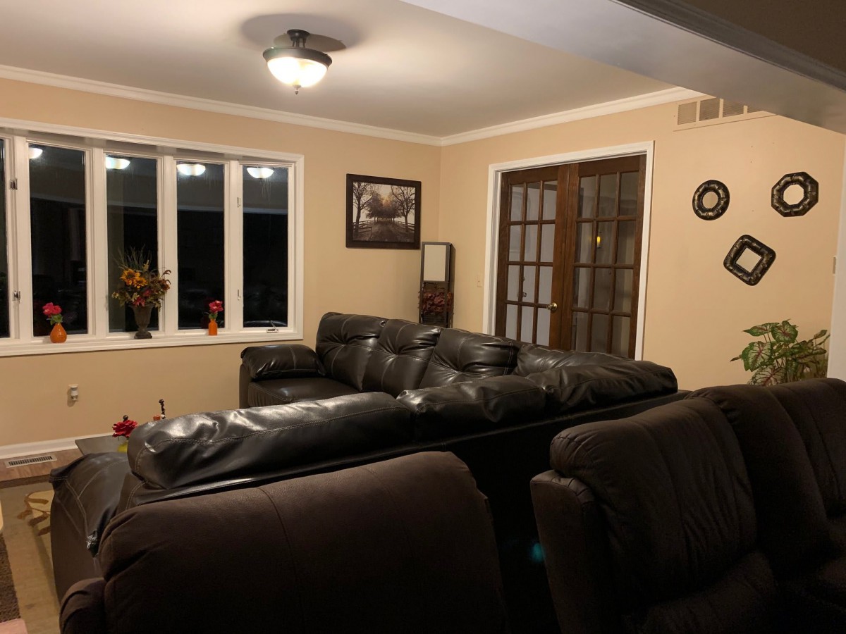 A cozy living room with a dark leather couch and large windows.