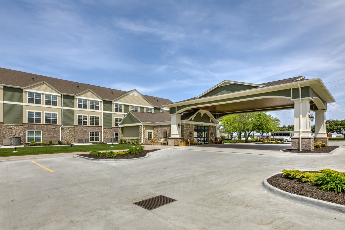An exterior view of a hotel with a covered entrance and landscaped surroundings.