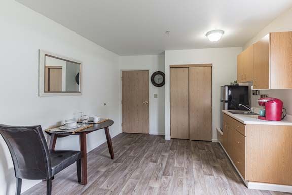 A minimalist kitchen with a wooden dining table and modern appliances.