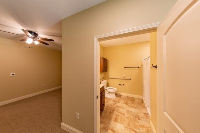 View of a room with an adjacent bathroom, showcasing beige walls and tiled flooring.