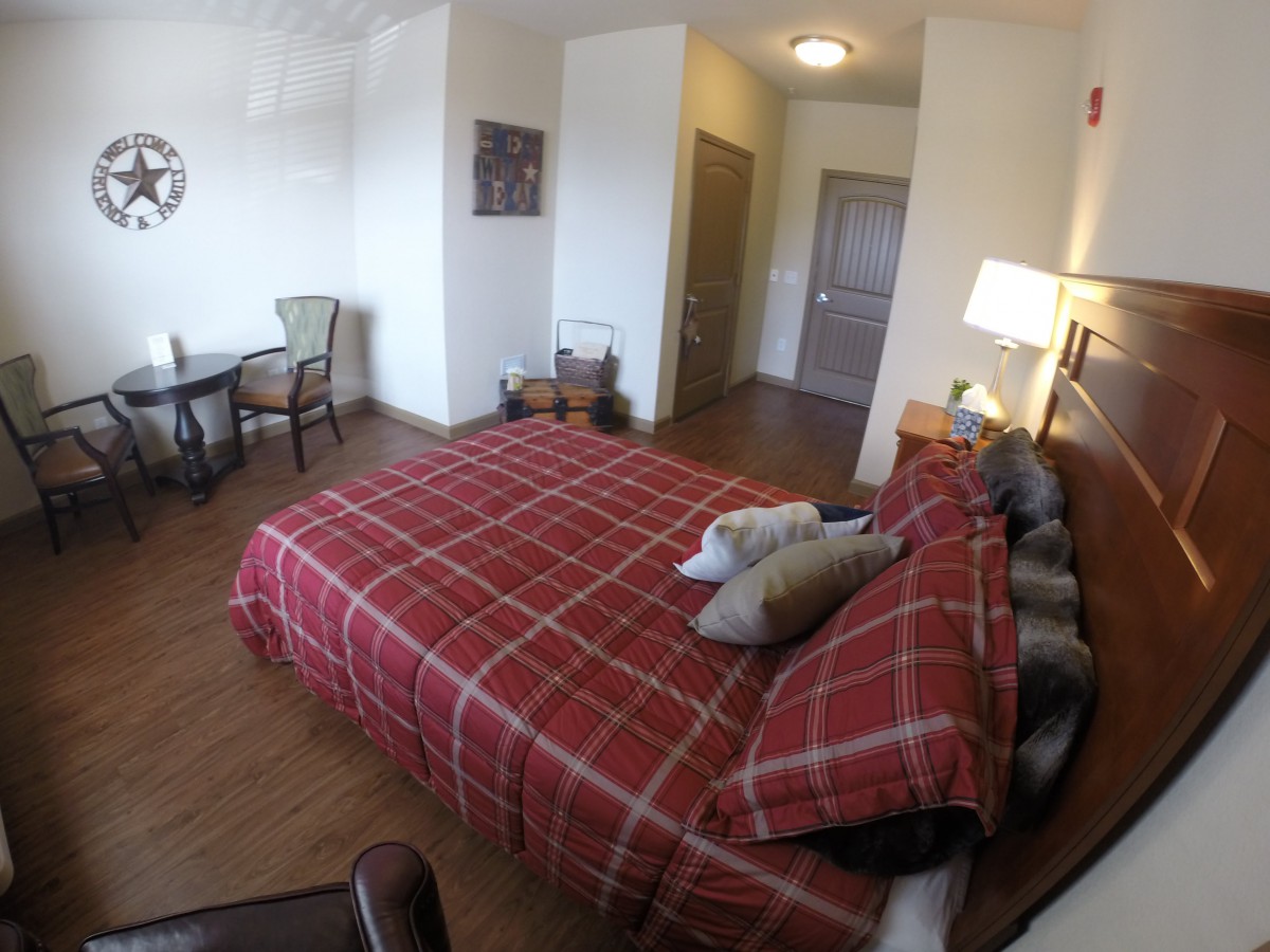 A cozy hotel room with a plaid-covered bed, side table, and seating area.