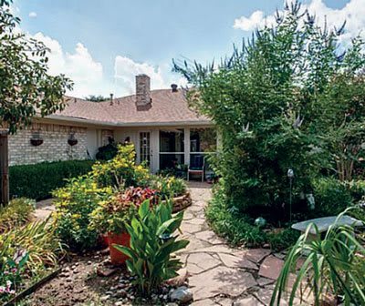 A lush garden with a variety of plants surrounding a cozy house patio.