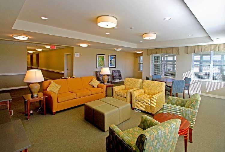 A cozy living room with various seating arrangements and warm lighting.