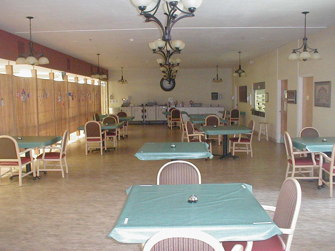 An empty dining area with neatly arranged tables and chairs, featuring a chandelier.