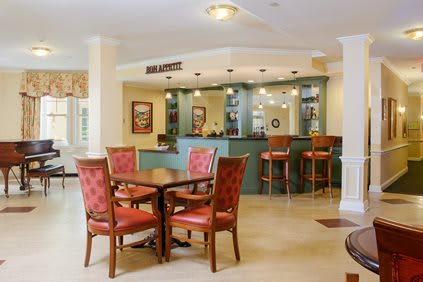 A cozy lobby with a seating area and bar counter, featuring elegant tables and chairs.