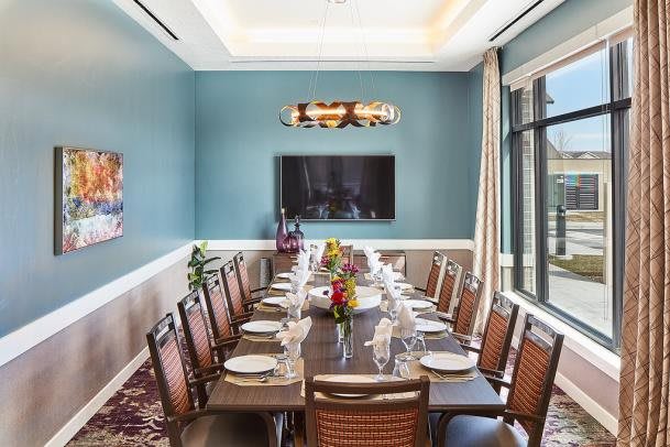 An elegantly set dining room with a long table and chairs, featuring stylish interior decor.