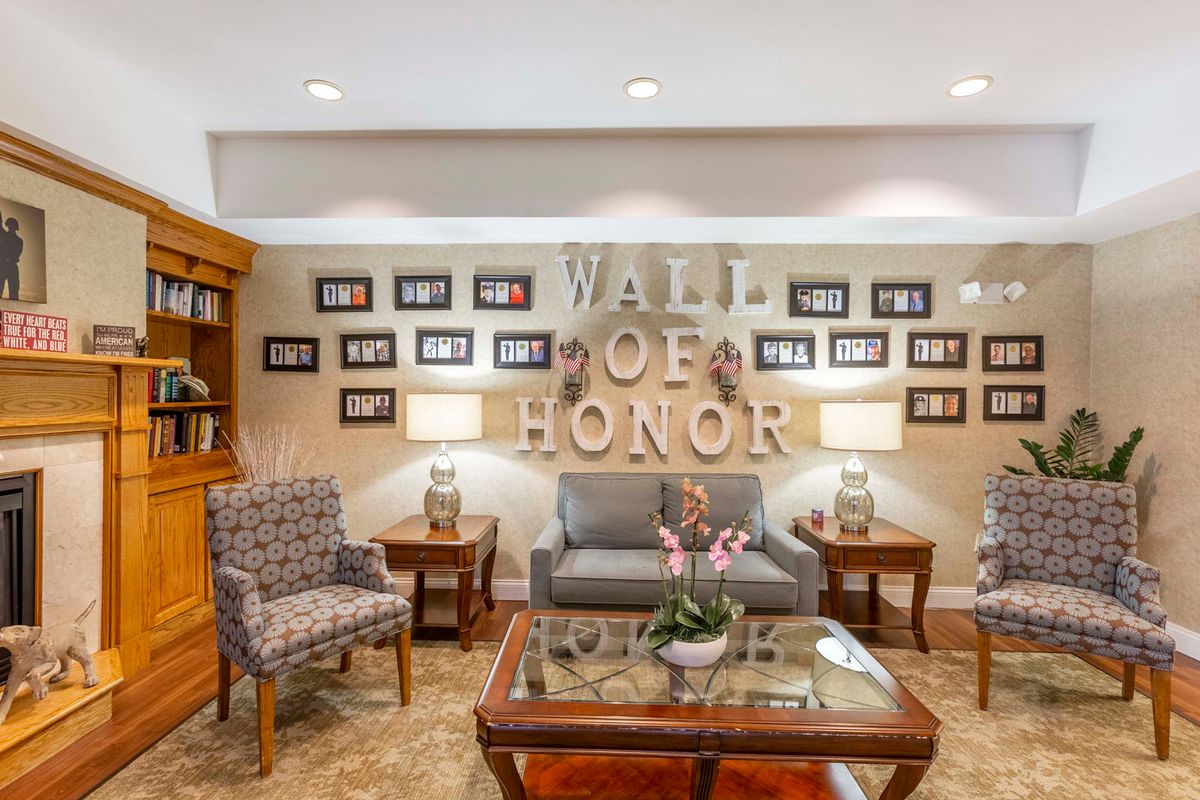 A cozy living room with a 'Wall of Honor' adorned with photographs, comfortable seating, and elegant decor.