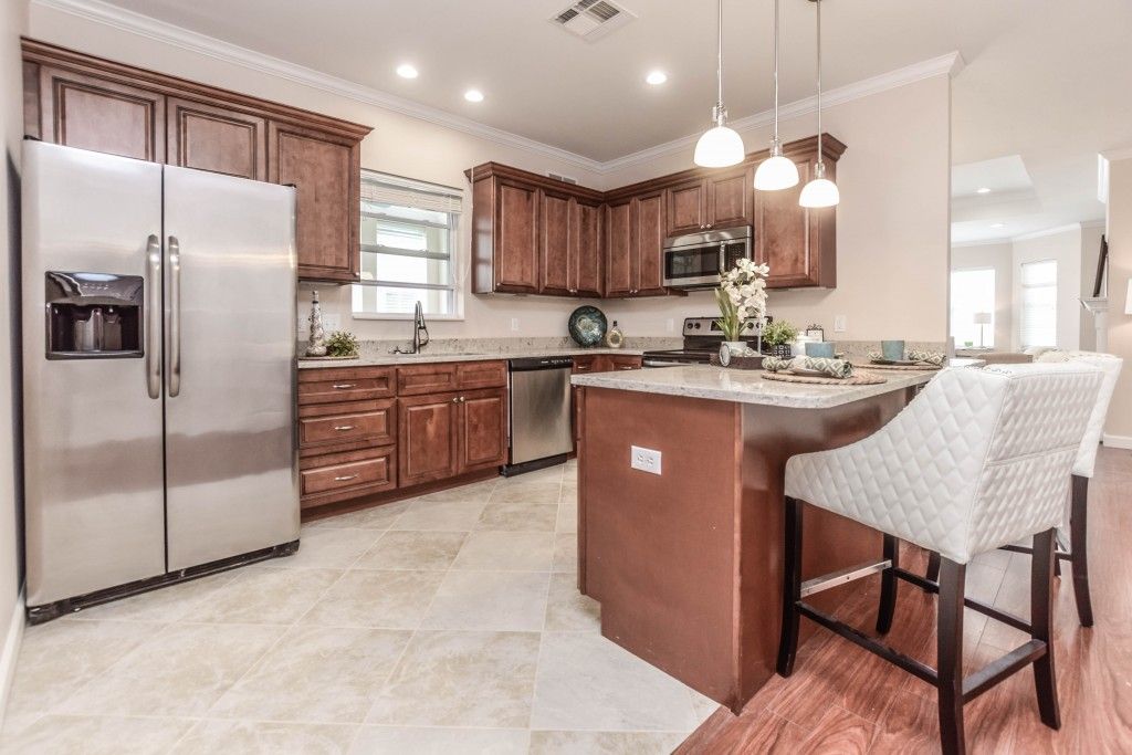 A modern kitchen featuring wooden cabinets, an island, and stainless steel appliances.
