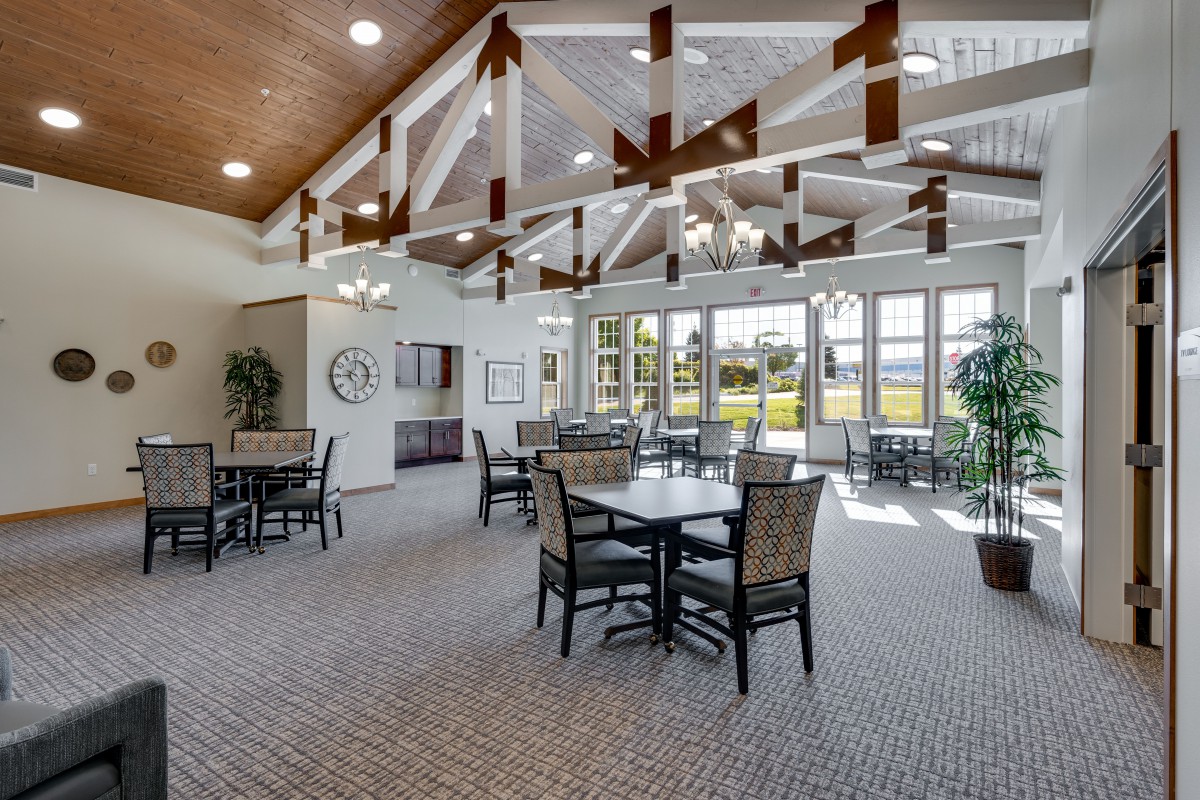 A spacious dining area with large windows and high ceilings adorned with wooden beams and chandeliers.