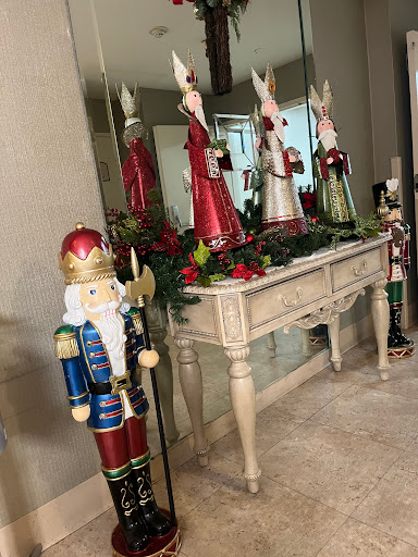 A festive holiday display featuring a nutcracker and colorful Christmas figurines adorning a mirrored table.