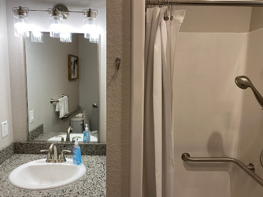 A glimpse into a neatly designed bathroom featuring a sink, mirror, and shower.