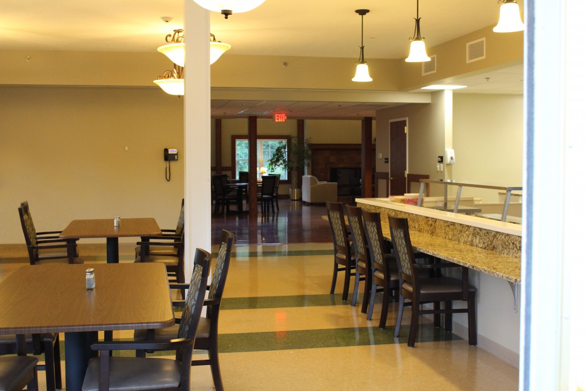 An empty dining area with neatly arranged tables and chairs, featuring modern lighting.