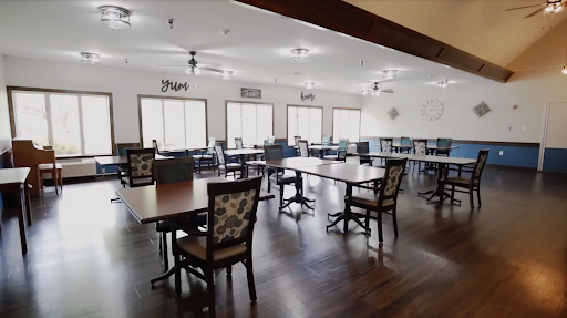 A spacious dining area featuring neatly arranged tables and chairs, illuminated by natural light from large windows.