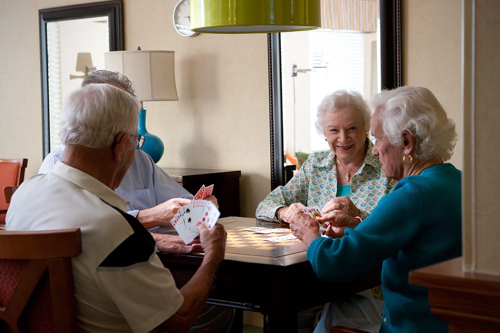 A group of elderly individuals enjoying a game of cards together indoors.