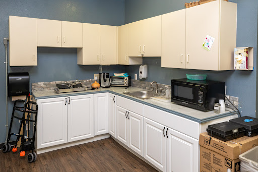 A modern kitchen featuring white cabinets, a countertop with a sink, and various appliances.