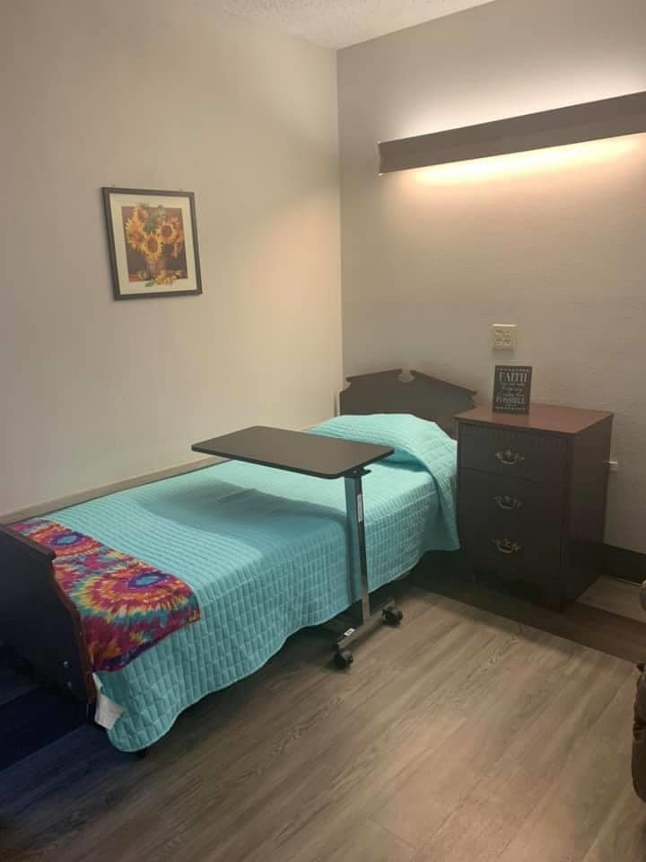 A tidy and minimalist room with a single bed, bedside table, and an overbed table.