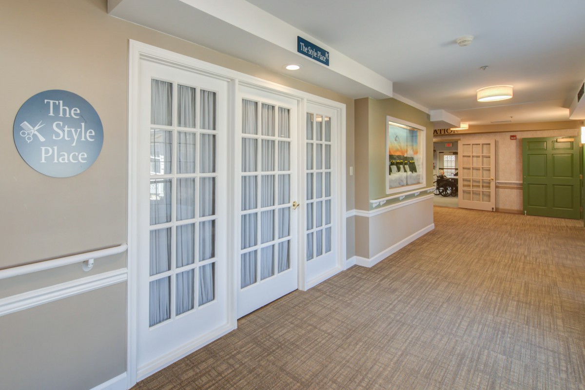 A bright hallway with French doors, wood flooring, and wall artwork.