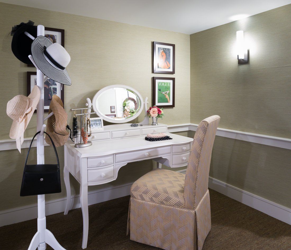 An elegant vanity setup with a mirror, chair, and hat stand in a tastefully decorated room.