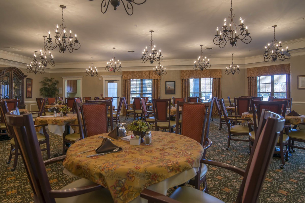 A spacious and elegantly decorated dining room with chandeliers and neatly arranged tables.