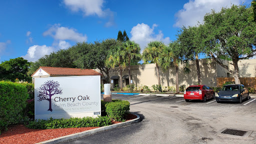 Entrance to Cherry Oak, featuring a sign and lush surroundings.