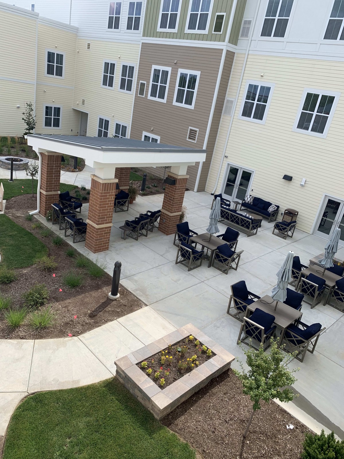A view of an outdoor patio area with several tables and chairs, adjacent to a building.