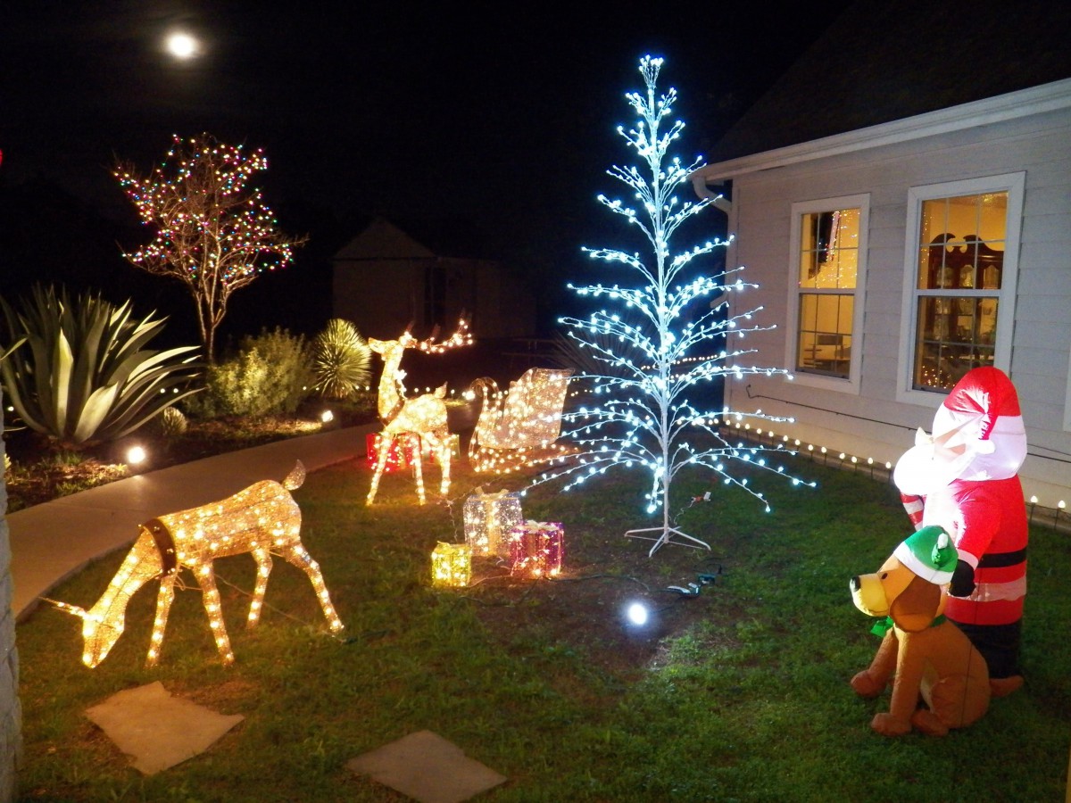 A festive outdoor Christmas display with illuminated reindeer and a glowing tree.