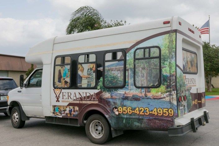 A bus with scenic artwork and contact information displayed on its side.