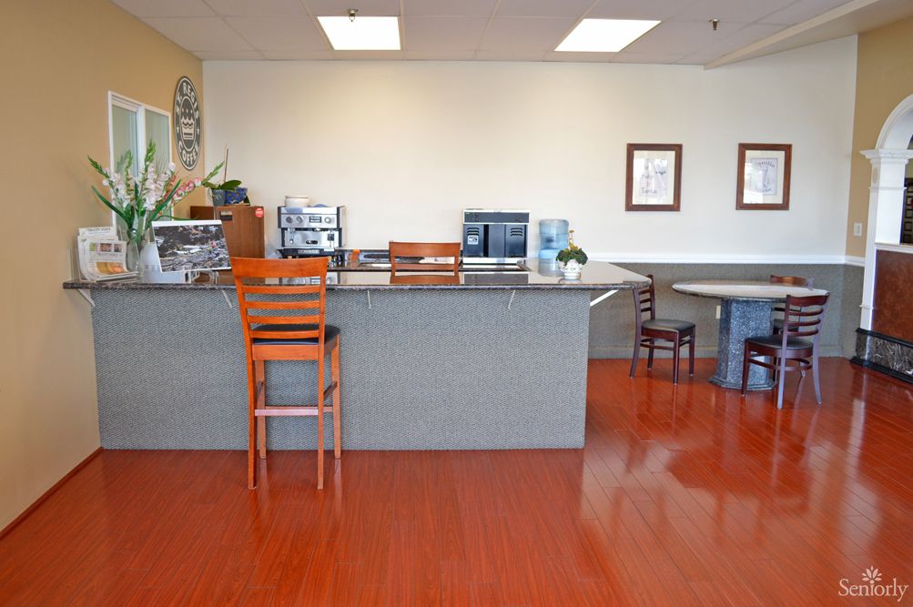A reception area with a counter and chairs, featuring hardwood floors.
