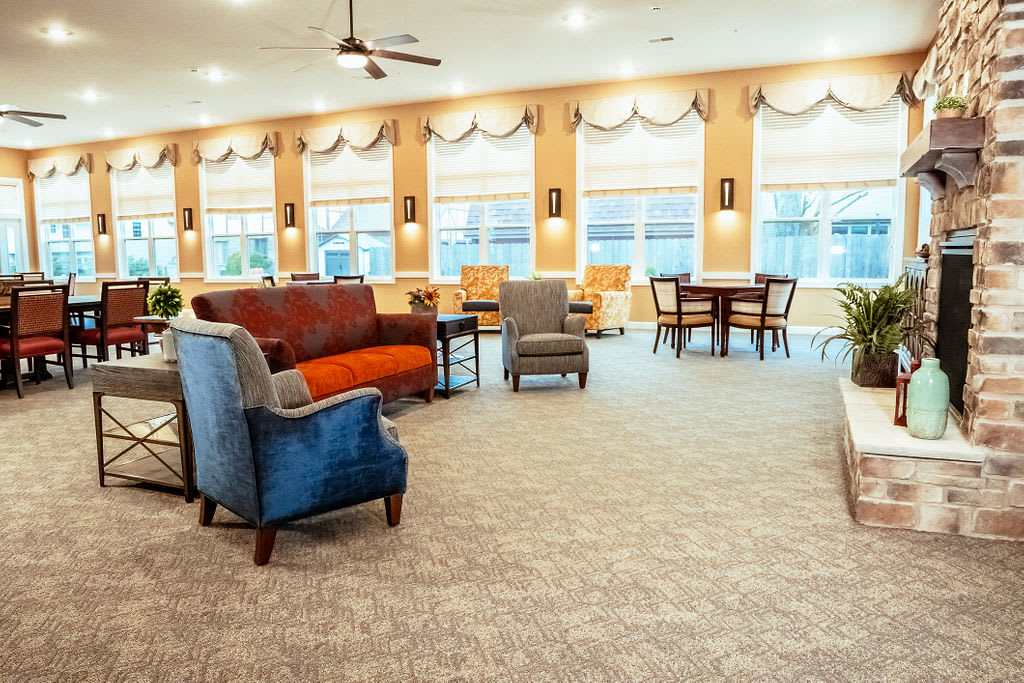 A spacious living room with comfortable seating, large windows, and warm lighting.