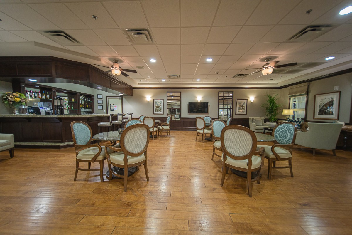A spacious dining area featuring elegant chairs and tables, with warm lighting and hardwood floors.