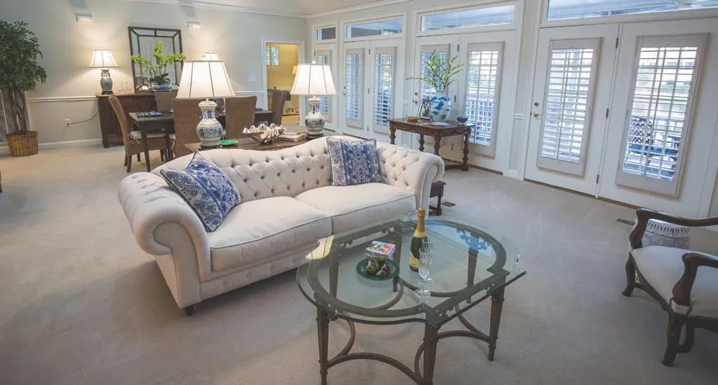 A well-lit living room featuring a stylish sofa with decorative pillows and a glass coffee table.