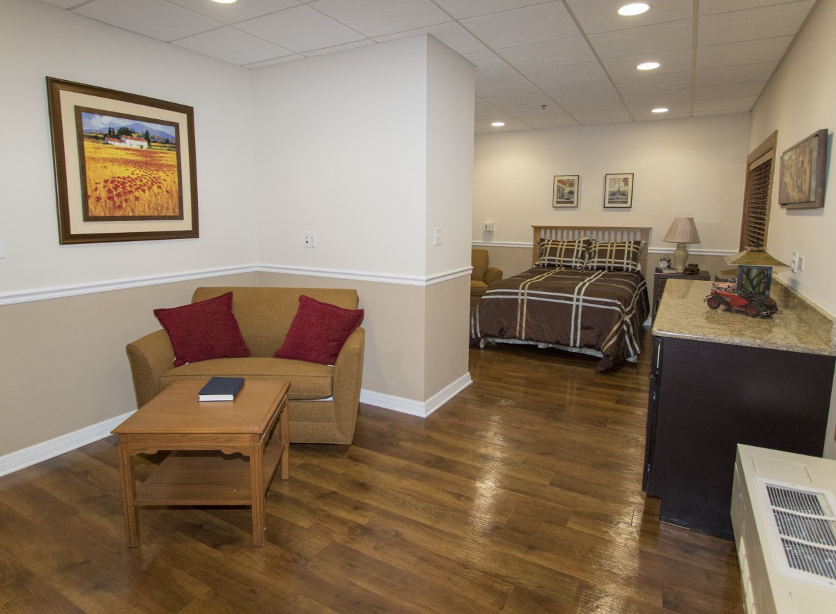 A cozy living space with a sofa and bed, featuring wooden floors and warm decor.
