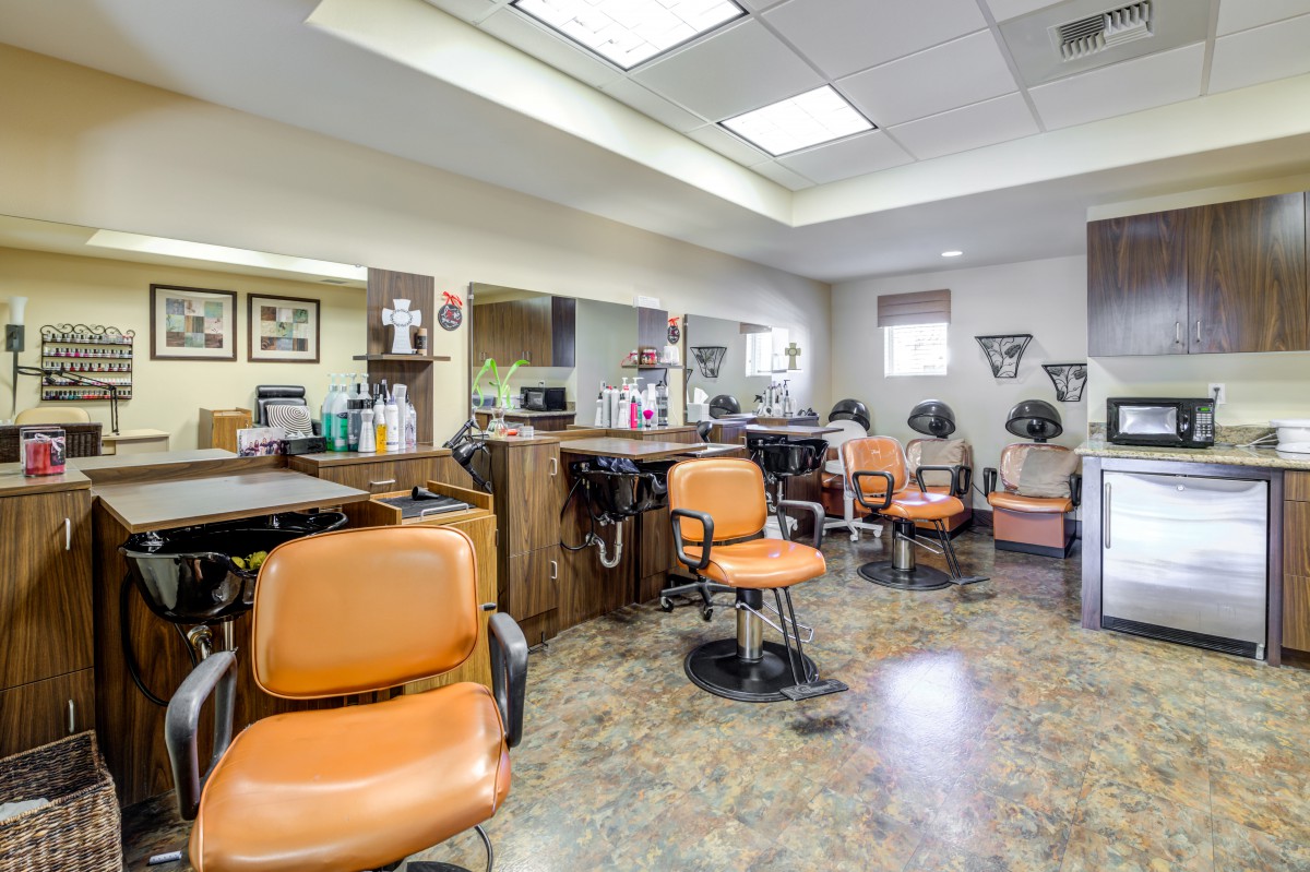 A well-equipped salon with multiple workstations and orange chairs.