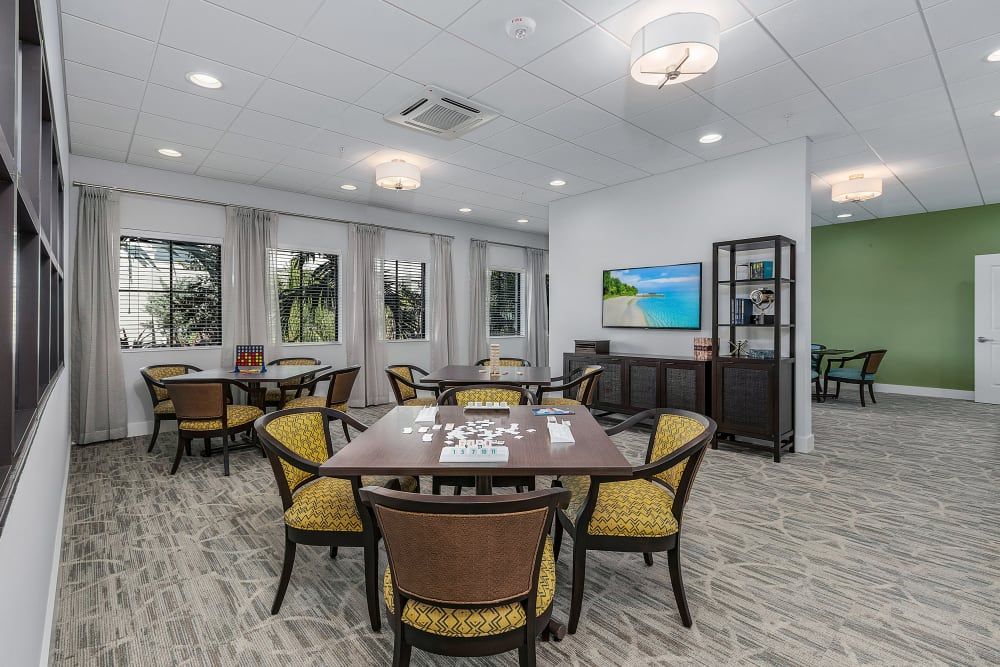 A modern dining room with multiple tables and chairs, featuring wall artwork and a television.
