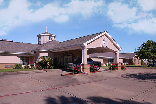 A large building with a covered entrance and driveway on a sunny day.