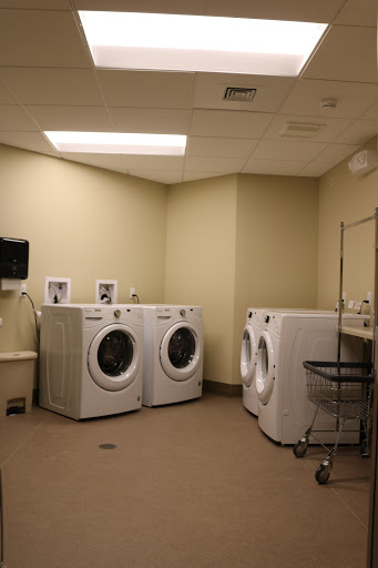 A clean and organized laundry room featuring multiple washing machines and a dryer.