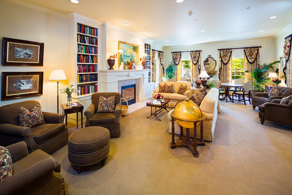A cozy and well-decorated living room featuring comfortable seating, a fireplace, and a bookshelf.