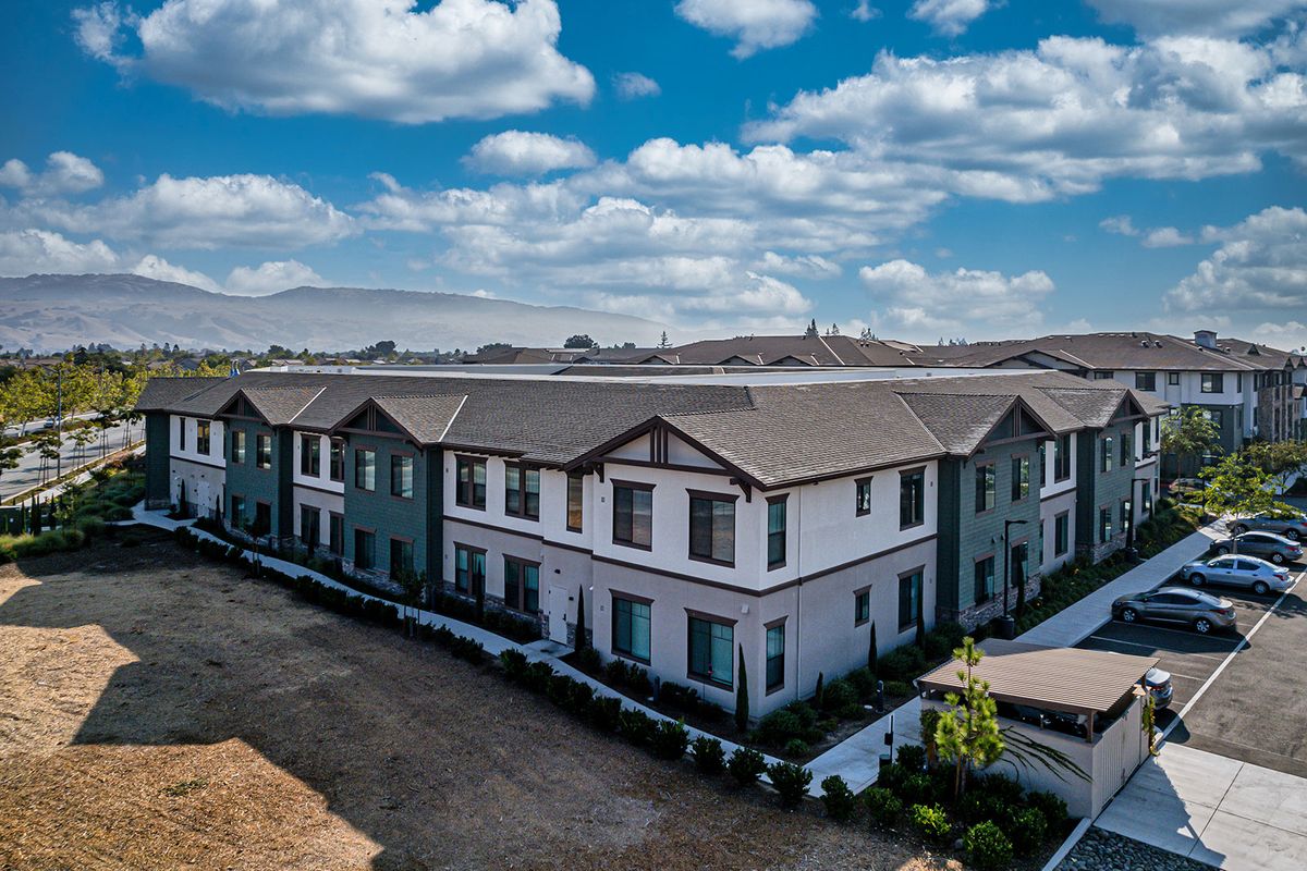 Aerial view of a modern residential building under a cloudy sky.
