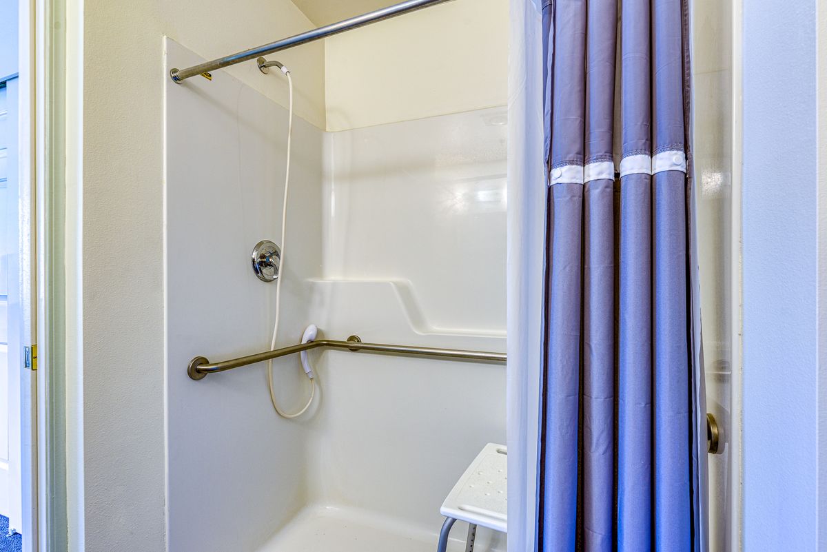 An accessible shower with grab bars and a shower curtain.