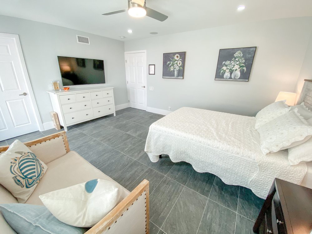 A modern, minimalist bedroom featuring a bed, dresser, and wall-mounted TV.