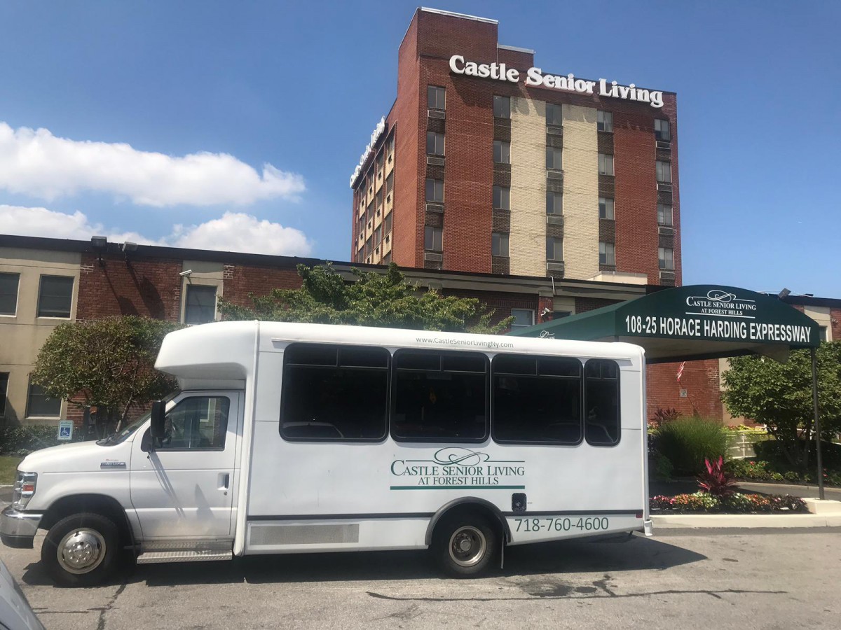 A shuttle bus parked in front of a senior living facility.