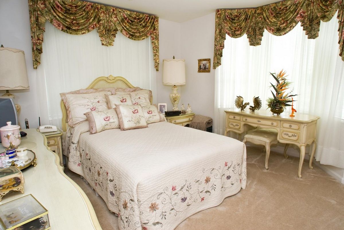 A classic bedroom with traditional decor including patterned drapes, a plush bed, and antique-style furniture.