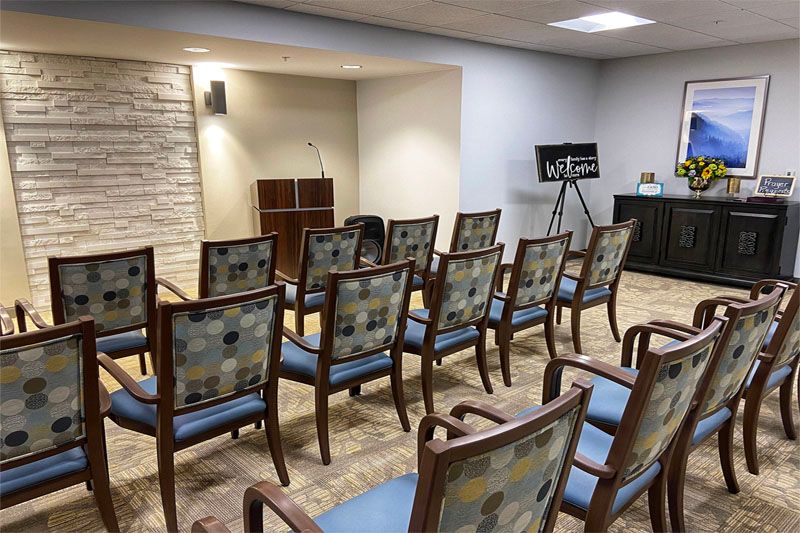 A small, neatly arranged conference room with a podium and rows of chairs.