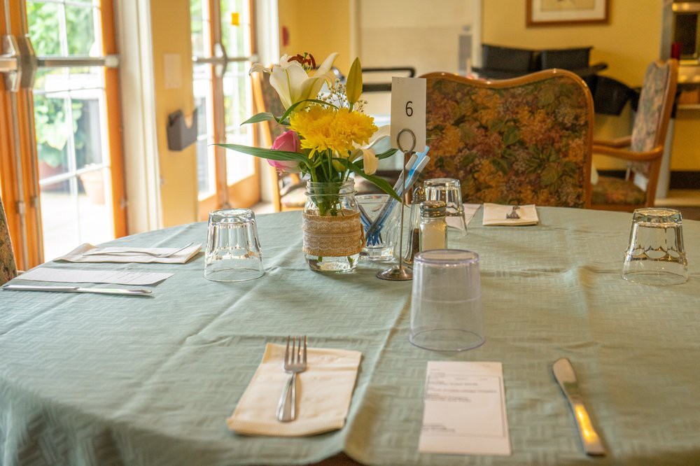 A neatly arranged dining table with a flower centerpiece and place settings.
