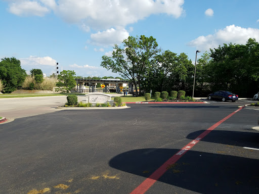A view of a parking lot with trees and a partially cloudy sky.