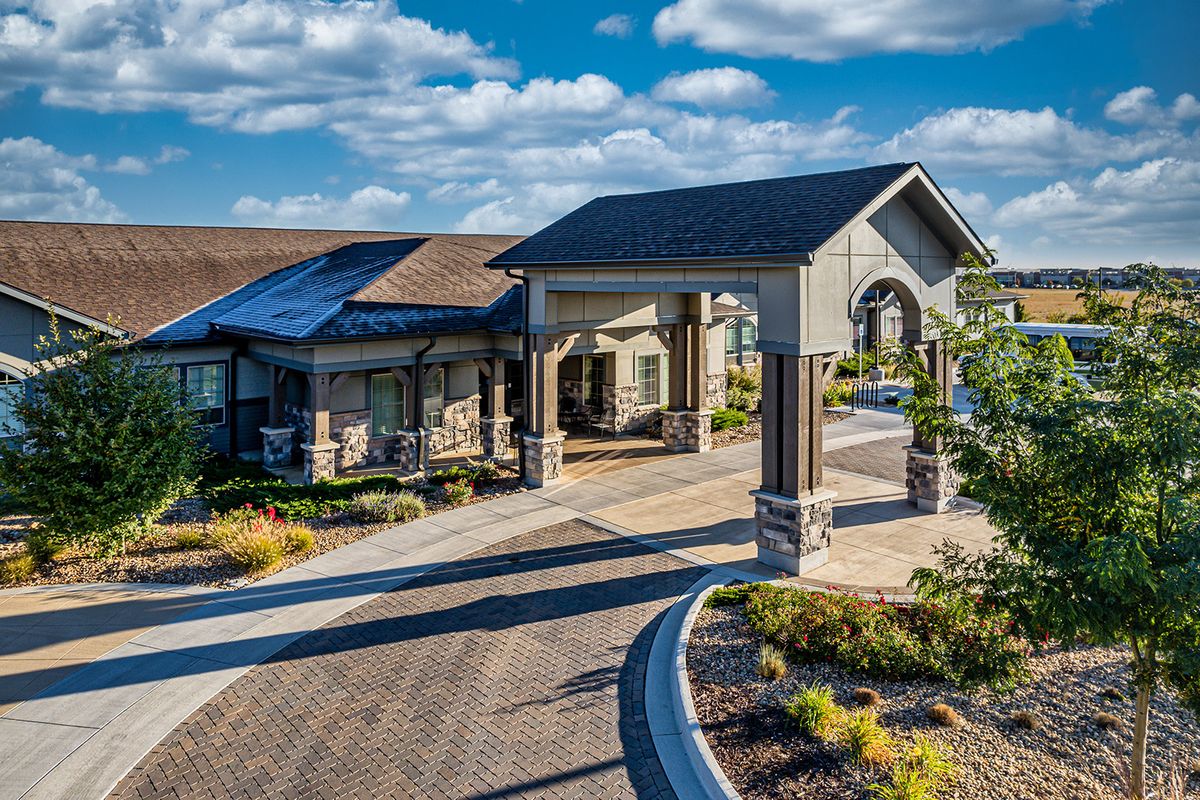 A modern residential building with a covered entrance and landscaped surroundings.