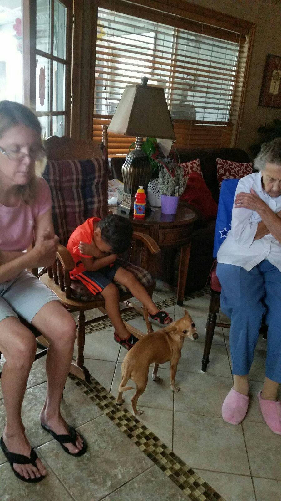 A family gathering in a living room with a small dog.