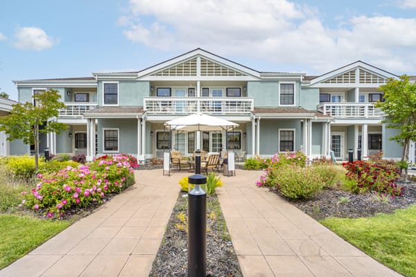 A picturesque residential building with symmetrical architecture, surrounded by well-maintained landscaping and a central pathway.