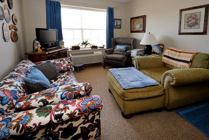 A cozy living room with a patterned sofa, armchairs, and a television.