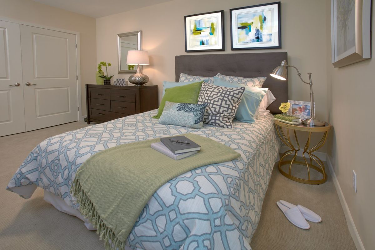 Cozy and stylish bedroom with patterned bedding and decorative pillows, featuring modern artwork above the bed.
